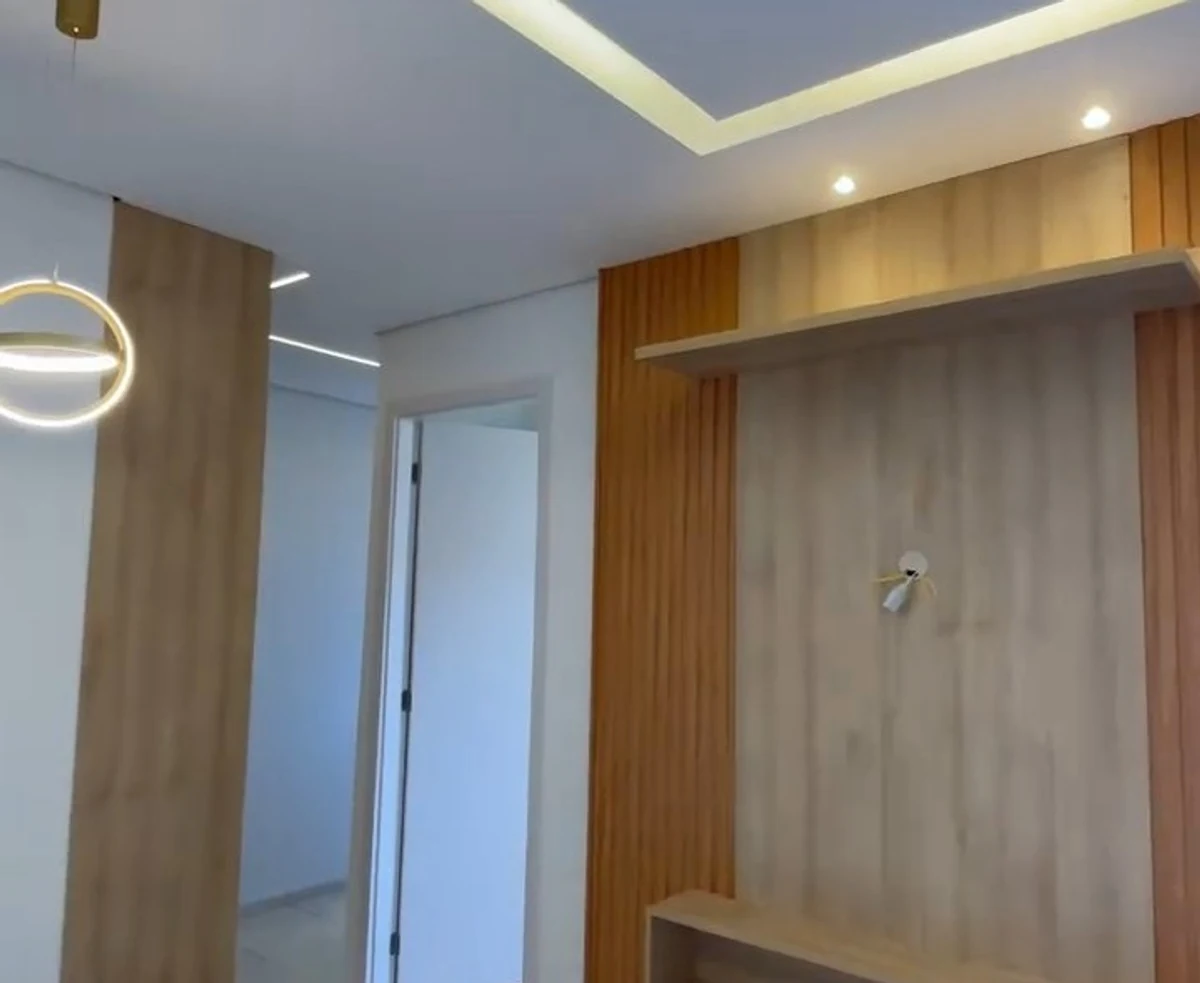 Sala com painel ripado de madeira, forro de gesso e sanca iluminada por fita de LED quente.