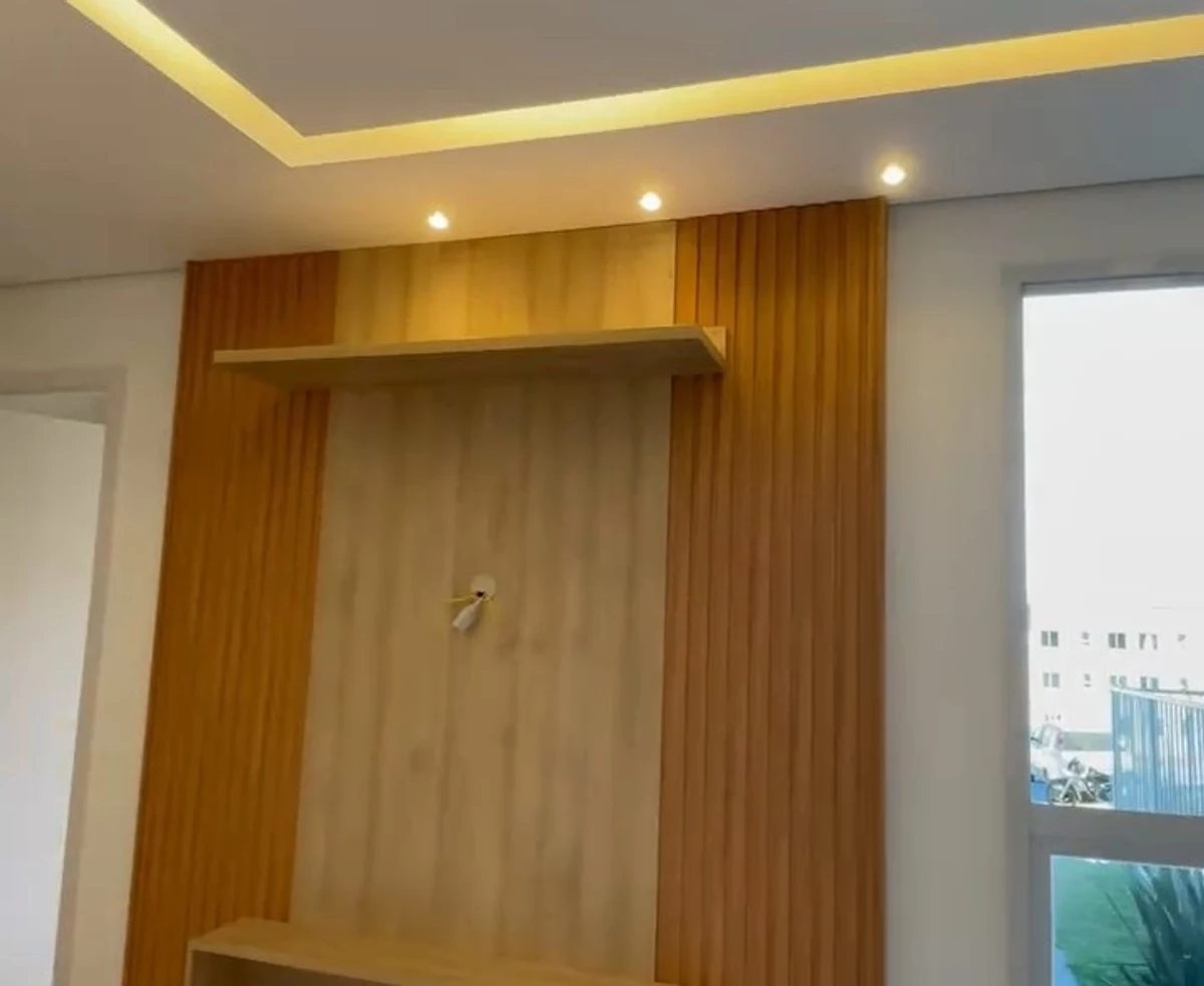 Sala de estar com forro, sanca iluminada e painel ripado.